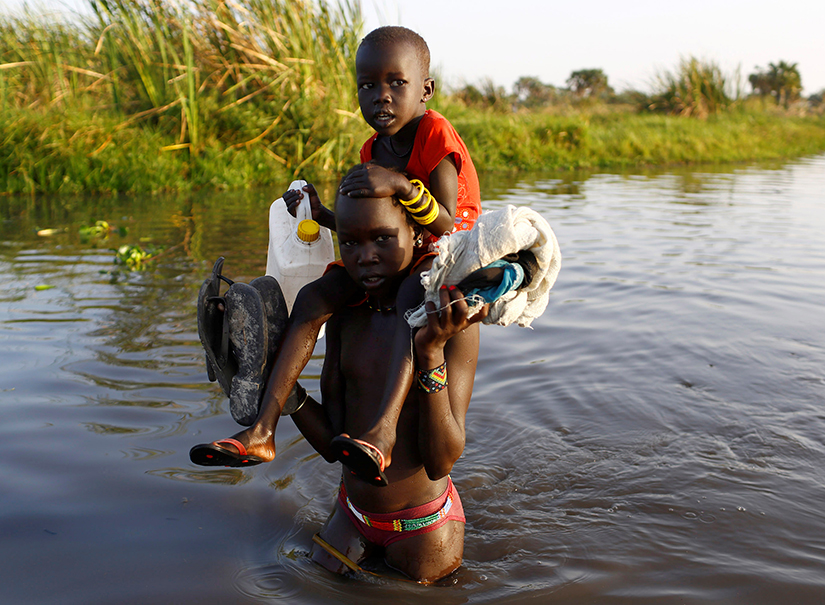 Children cross a body of water in South Sudan in 2017. They are on their way to a food distribution centre. (Siegfried Modola/Reuters)
